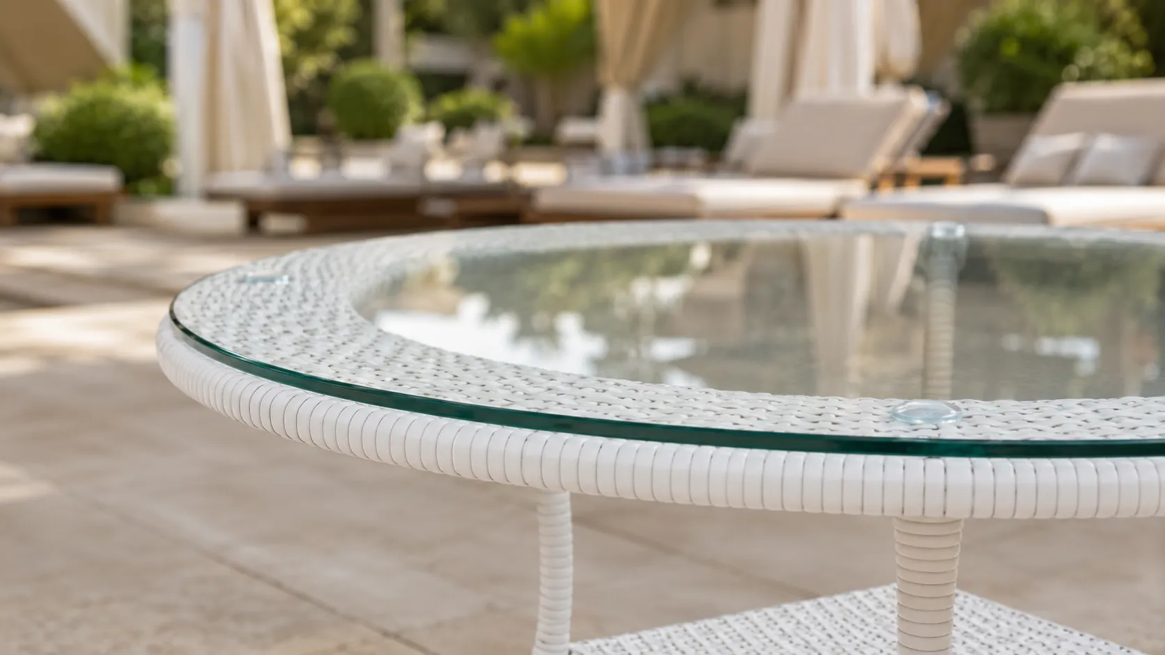 Round glass tabletop detail of white wicker outdoor table